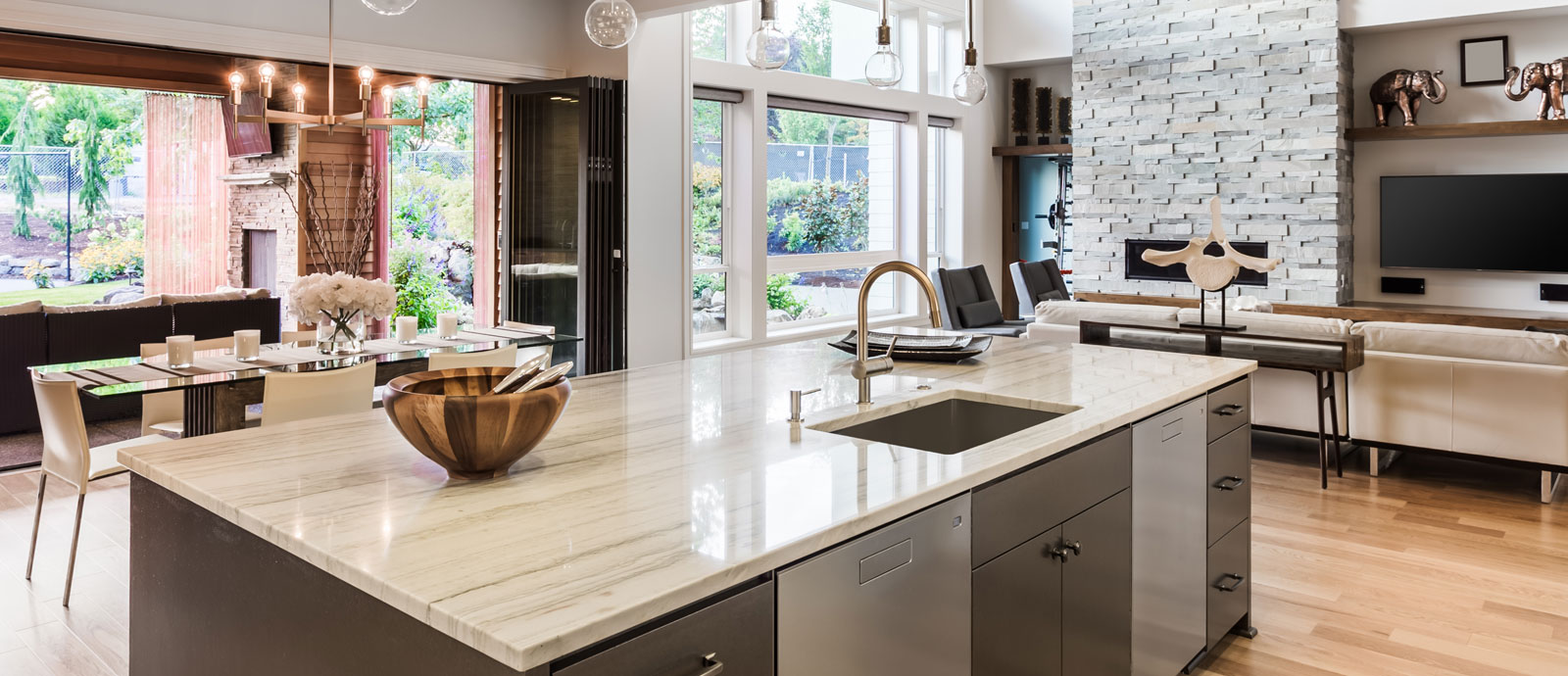 Kitchen island with built-in sink topped with beige stone with horizontal gray veining