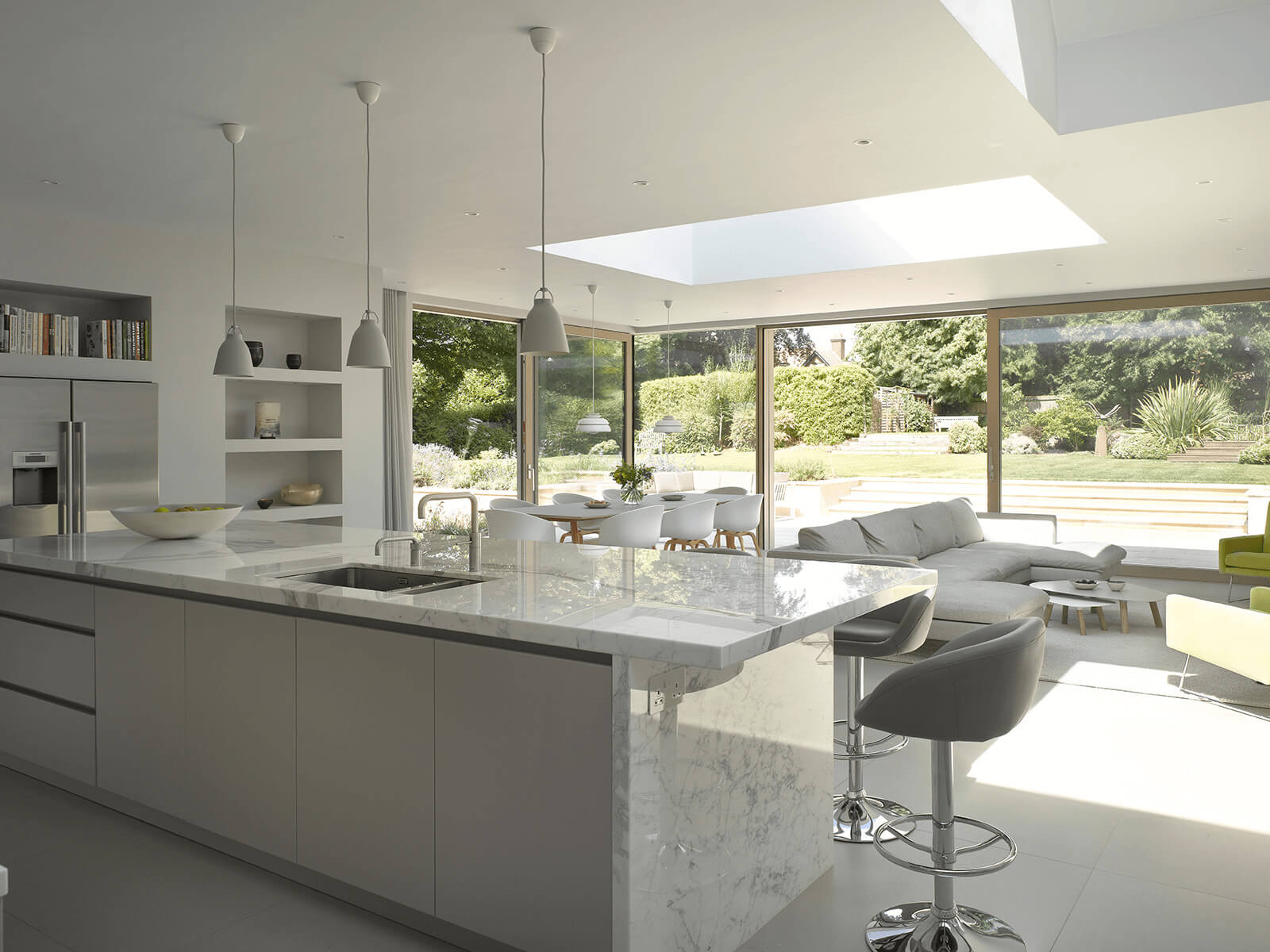 Kitchen island with white marble countertop with subtle gray veining, integrated sink and bar seating
