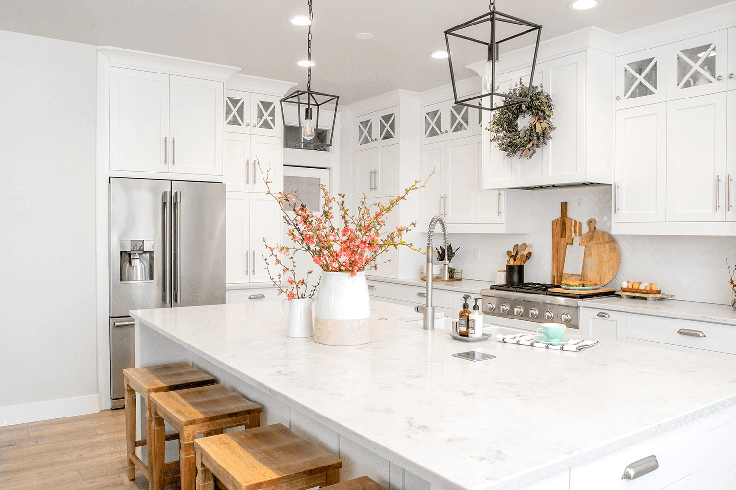 Kitchen island with light quartz countertop with subtle gray veining, sink and wooden stools