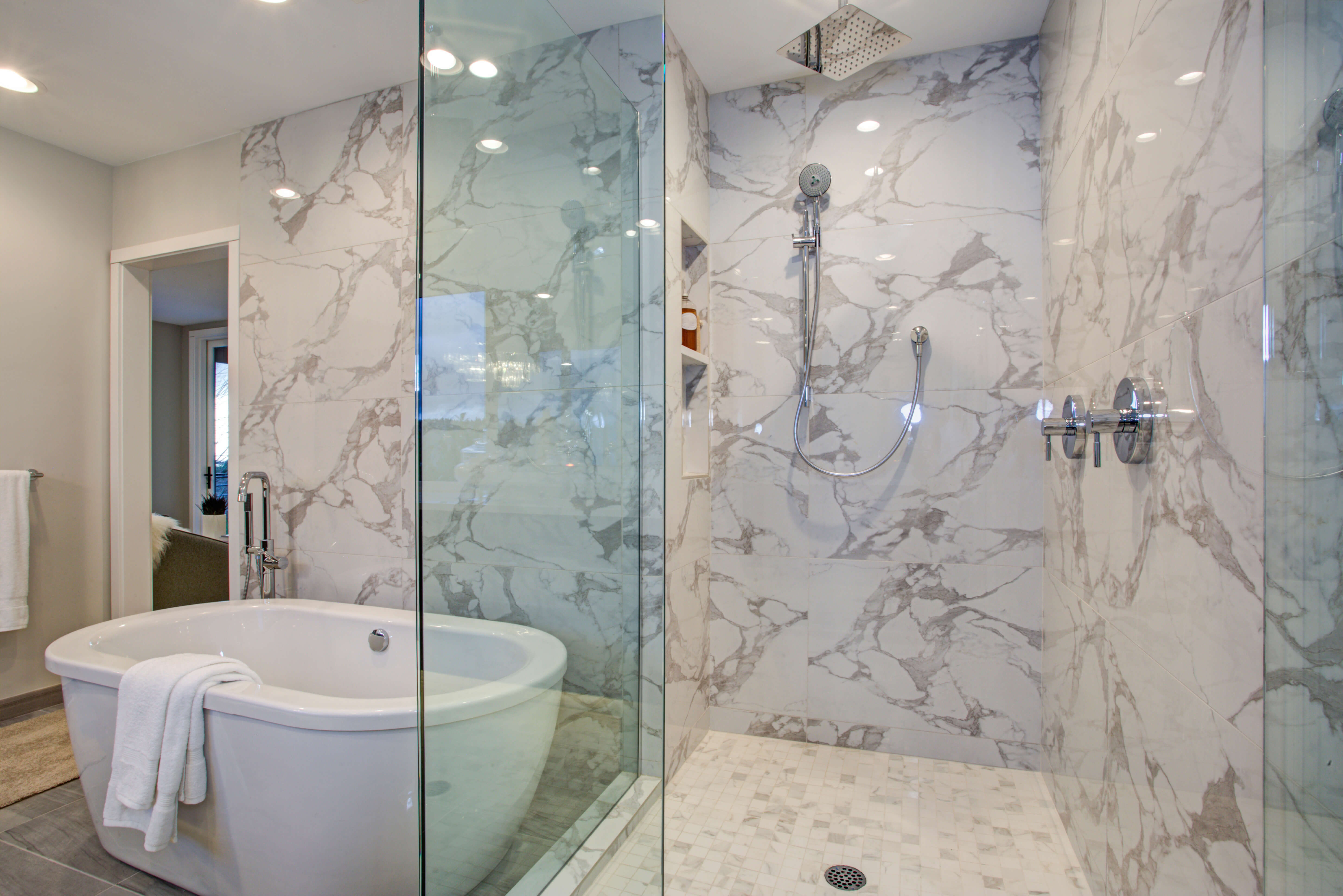 Tub and shower surrounds in large white stone panels with thick gray veining